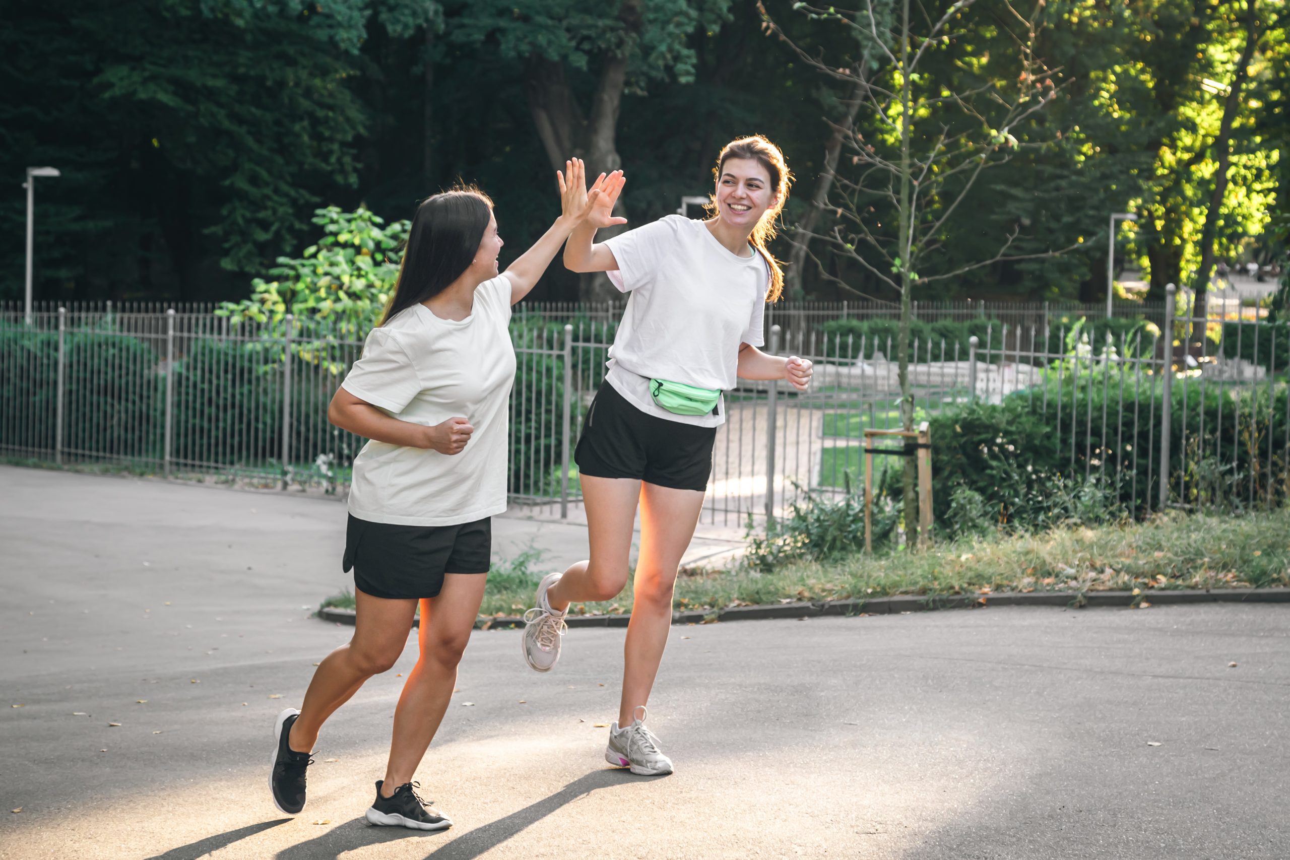 Two young attractive women jogging in the park at sunset, sporting together.