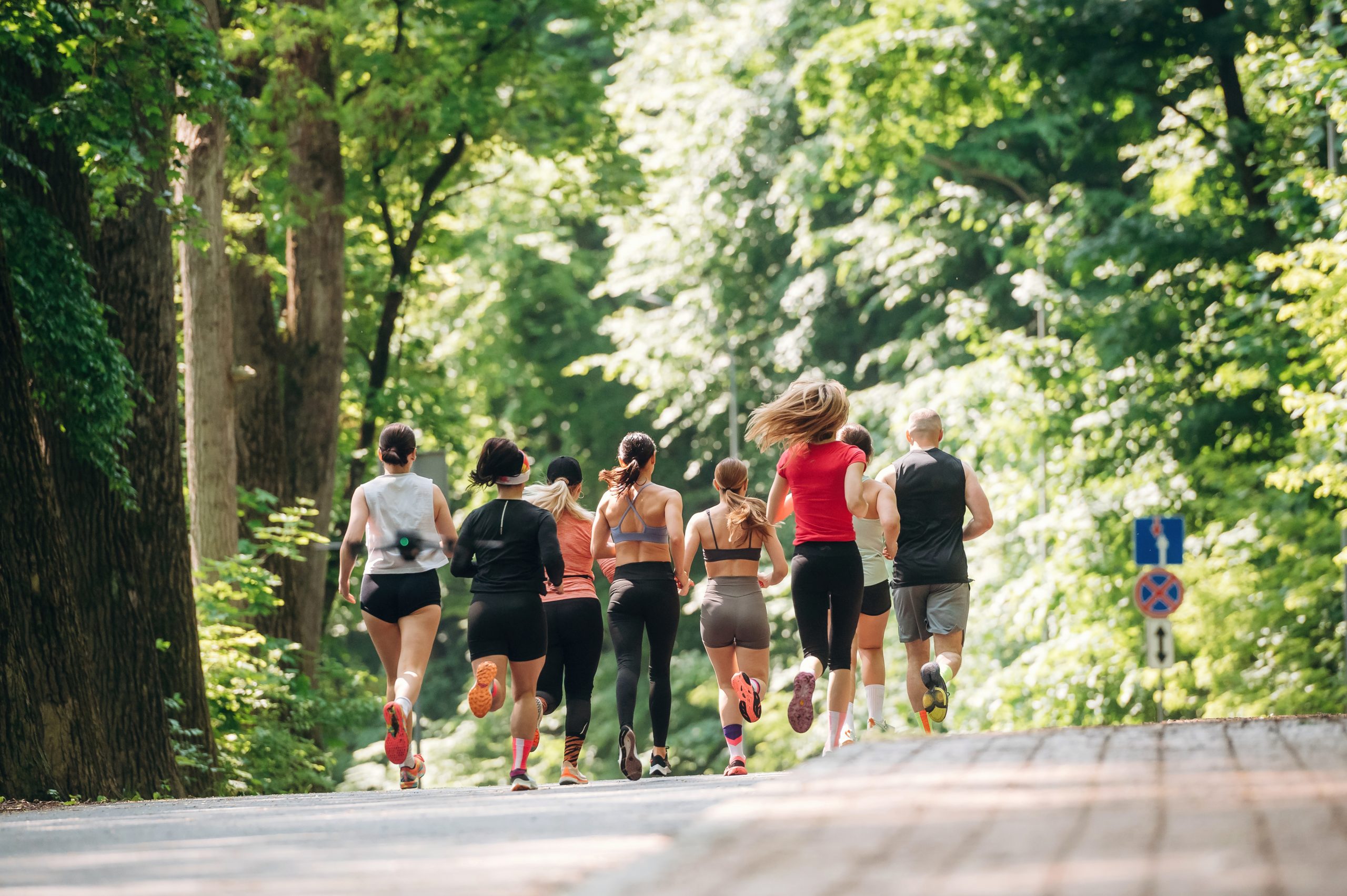 Adults are running together. Group of people are outdoors.